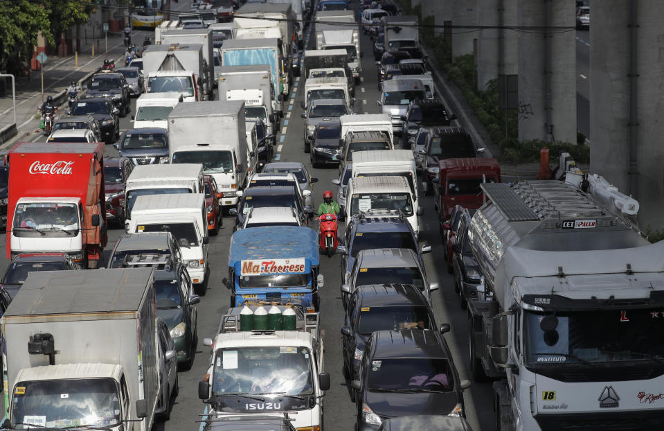 A motorbike rider negotiates traffic as it snarls due to a police checkpoint on the outskirts of Manila, Philippines on Monday, May 18, 2020. Crowds and vehicular traffic returned to shopping malls in the Philippine capital after a two-month coronavirus lockdown was partially relaxed over the weekend, prompting police to warn of arrests and store closures. (AP Photo/Aaron Favila)