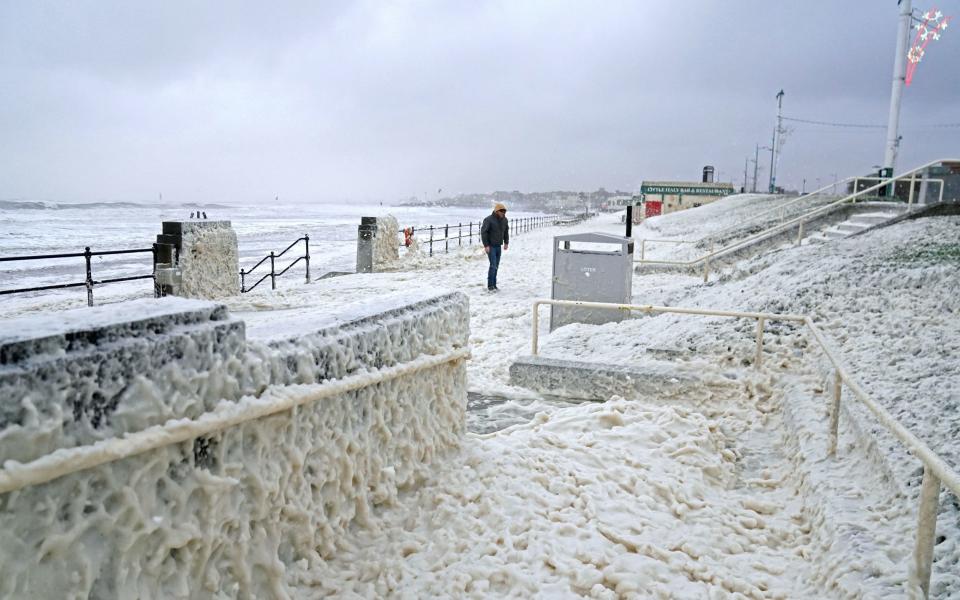 A man walks through sea foam in Seaburn, Sunderland, as Storm Babet batters the country