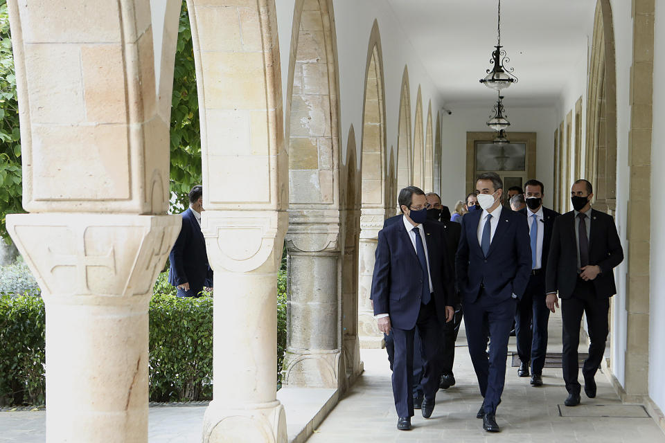 This image provided from Cyprus' press and information office, Cyprus President Nicos Anastasiades, left, and Greece's Prime minister Kyriakos Mitsotakis talk as they walk after their meeting at the presidential palace in capital Nicosia, Cyprus, on Monday, Feb. 8, 2021. Mitsotakis is in Cyprus for one-day official visit. (Stavros Ioannides, PIO via AP)