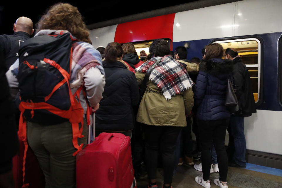 Commuters try to enter a subway train Tuesday, Dec. 10, 2019 in Paris. Only about a fifth of French trains ran normally Tuesday, frustrating tourists finding empty train stations, and most Paris subways were at a halt. French airport workers, teachers and others joined nationwide strikes Tuesday as unions cranked up pressure on the government to scrap changes to the national retirement system. (AP Photo/Francois Mori)