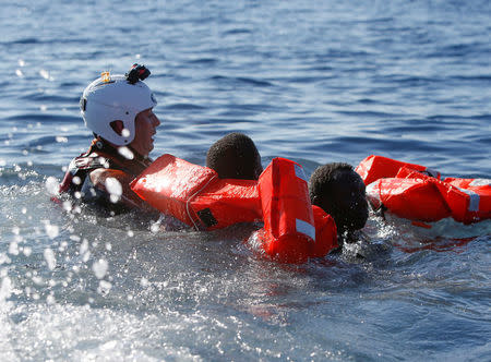 A rescue swimmer holds onto migrants frantically trying to stay afloat after falling off their rubber dinghy during a rescue operation by the Malta-based NGO Migrant Offshore Aid Station (MOAS) ship in the central Mediterranean in international waters some 15 nautical miles off the coast of Zawiya in Libya, April 14, 2017. REUTERS/Darrin Zammit Lupi