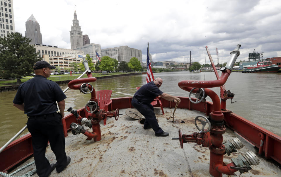Firemen maintain the Anthony J. Celebrezze as it floats down the Cuyahoga River, Thursday, June 13, 2019, in Cleveland. The fire boat extinguished hot spots on a railroad bridge torched by burning fluids and debris on the Cuyahoga River in 1969. (AP Photo/Tony Dejak)