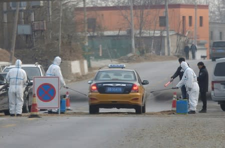 FILE PHOTO: Workers in protective suits are seen at a checkpoint on a road leading to a village near a farm where African swine fever was detected, in Fangshan district of Beijing