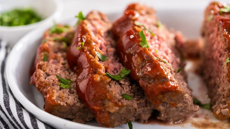 Meatloaf slices on a plate with herbs