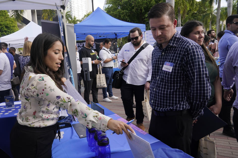 Lauren Rosario shows Anthony Gratta the job openings at Kaseya, an IT software company, during the Venture Miami Tech Hiring Fair Thursday, April 14, 2022, in Miami. America’s employers added 428,000 jobs in April, extending a streak of solid hiring that has defied punishing inflation, chronic supply shortages, the Russian war against Ukraine and much higher borrowing costs. (AP Photo/Marta Lavandier)
