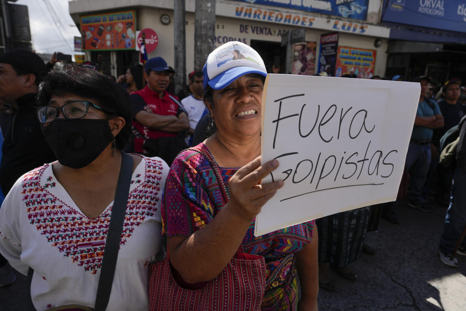 A demonstrator holds the Spanish sign "Get out coup plotters" at a protest demanding the resignation of Attorney General Consuelo Porras and prosecutor Rafael Curruchiche in Guatemala City, Monday, Oct. 2, 2023. Indigenous organizations are blocking some roads across the country to protest the attorney general's latest raids on Guatemala’s top electoral tribunal after elections. (AP Photo/Moises Castillo)