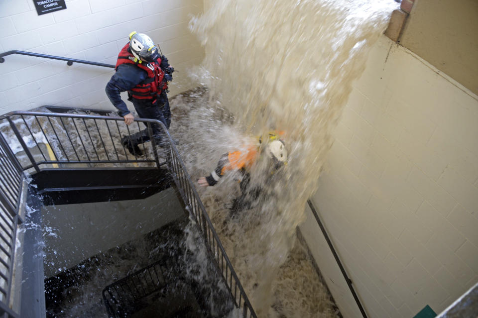 Workers walk down stairs to a parking structure as water cascades down on them on the UCLA campus after flooding from a broken 30-inch water main under nearby Sunset Boulevard inundated a large area of the campus in the Westwood section of Los Angeles, Tuesday, July 29, 2014. The 30-inch (75-centimeter) 93-year-old pipe that broke made a raging river of the street and sent millions of gallons (liters) of water across the school's athletic facilities, including the famed floor of Pauley Pavilion, the neighboring Wooden Center and the Los Angeles Tennis Center, and a pair of parking structures that took the brunt of the damage. (AP Photo/Mike Meadows)