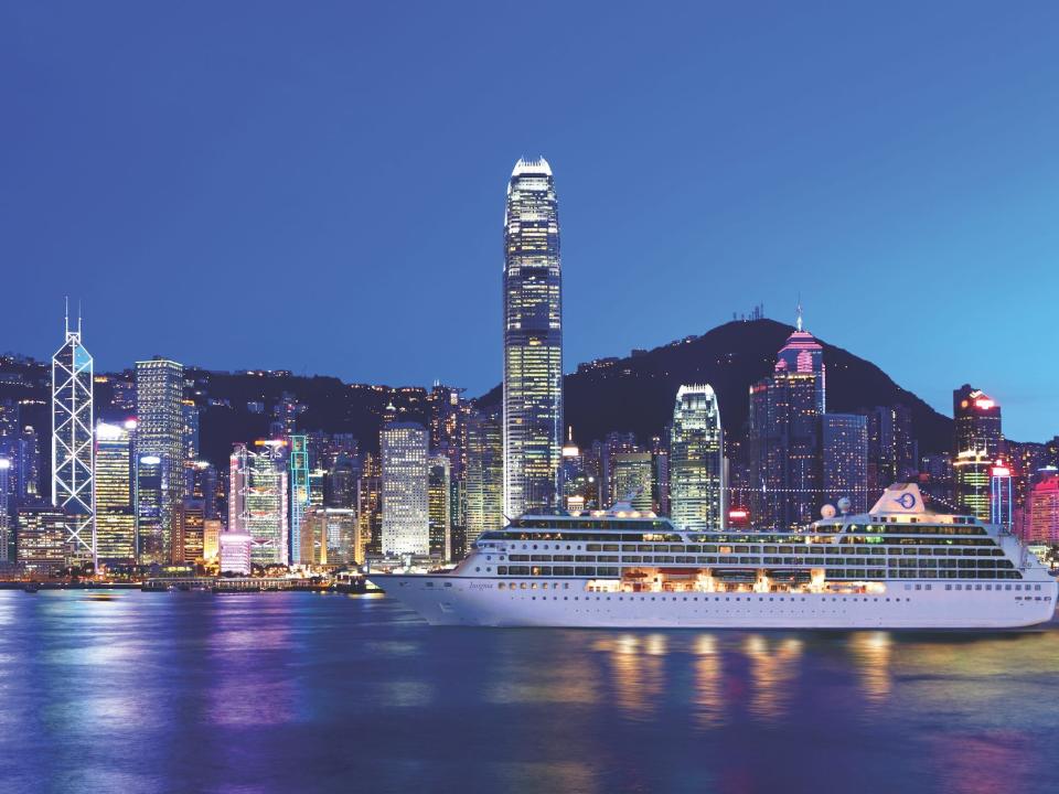 The Insignia sailing on a body of water in front of a city at night.