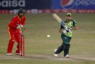 Pakistani batsman Khushdil Shah, right, plays a shot while Zimbabwe's wicketkeeper Brendan Taylor watches, during the 3rd Twenty20 cricket match at the Pindi Cricket Stadium, in Rawalpindi, Pakistan, Tuesday, Nov. 10, 2020. (AP Photo/Anjum Naveed)