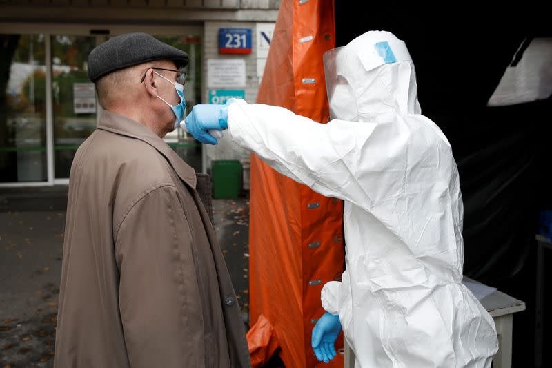FILE PHOTO: A man in protective suit checks a man's temperature in Warsaw