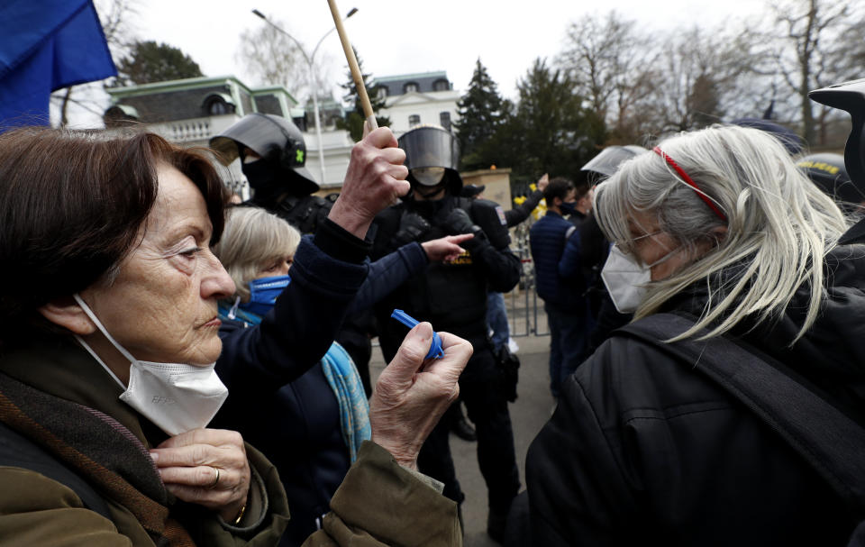 A woman blows a whistle in front of the Russian Embassy in Prague, Czech Republic, Sunday, April 18, 2021. Czech Republic is expelling 18 diplomats identified as spies over a 2014 ammunition depot explosion. On Saturday, Prime Minister Andrej Babis said the Czech spy agencies provided clear evidence about the involvement of Russian military agents in the massive explosion that killed two people. (AP Photo/Petr David Josek)