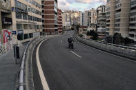 A food deliveryman on a scooter moves on an empty street during a lockdown aimed at curbing the spread of the coronavirus, in Beirut, Lebanon, Friday, Jan. 15, 2021. Lebanon's parliament has approved a draft law to allow the importing of vaccines into the tiny country to fight the spread of coronavirus. (AP Photo/Bilal Hussein)