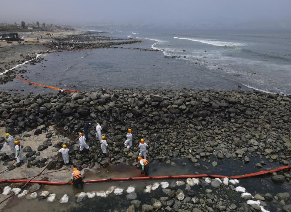 Workers continue in a clean-up campaign after an oil spill, on Pocitos Beach in Ancon, Peru, Tuesday, Feb. 15, 2022. One month later, workers continue the clean-up beaches after contamination by a Repsol oil spill. (AP Photo/Martin Mejia)