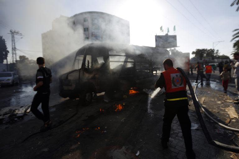Palestinian firefighters try to extinguish the flames in a van that was reportedly targeted by an Israeli military strike, in Gaza City on July 31, 2014