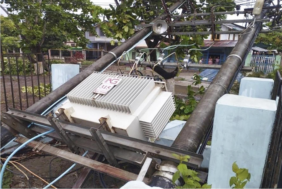 In this photo provided by Myanmar Military True News Information Team on Sunday, May 14, 2023, a lamppost attached with electrical transformer damaged by Cyclone Mocha lines on a street in Gwa township, Rakhine State. (Military True News Information Team via AP)