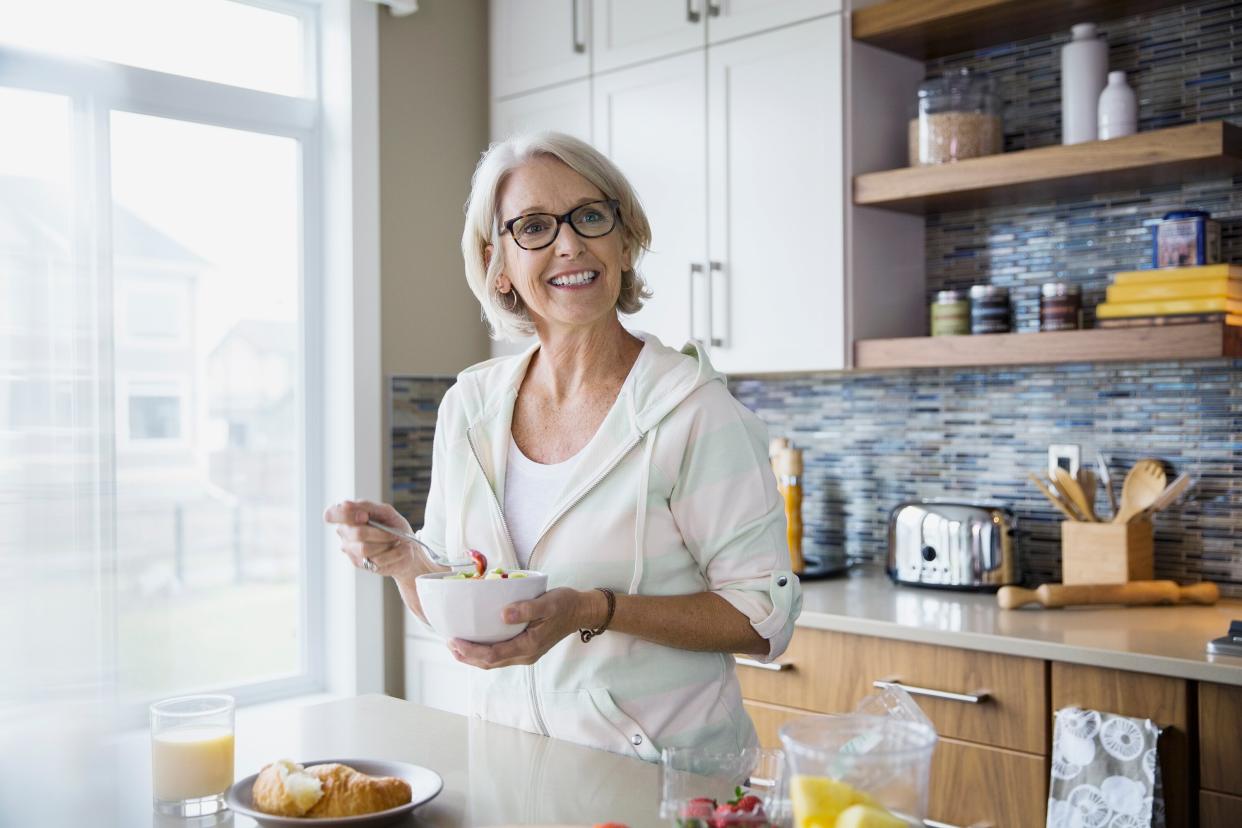 Woman Eating Salad While Standing in Kitchen