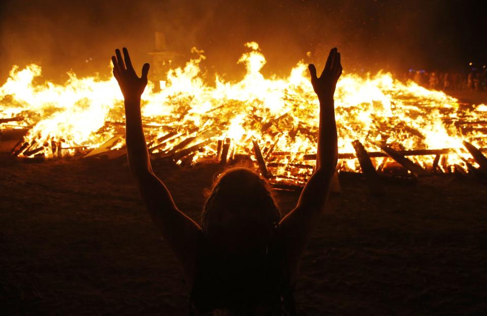 A Burning Man participant pays homage to the Temple of Whollyness as it burns at the conclusion of the 2013 Burning Man arts and music festival in the Black Rock desert of Nevada, late September 1, 2013. REUTERS/Jim Bourg (UNITED STATES - Tags: SOCIETY) FOR USE WITH BURNING MAN RELATED REPORTING ONLY. FOR EDITORIAL USE ONLY. NOT FOR SALE FOR MARKETING OR ADVERTISING CAMPAIGNS. NO THIRD PARTY SALES. NOT FOR USE BY REUTERS THIRD PARTY DISTRIBUTORS