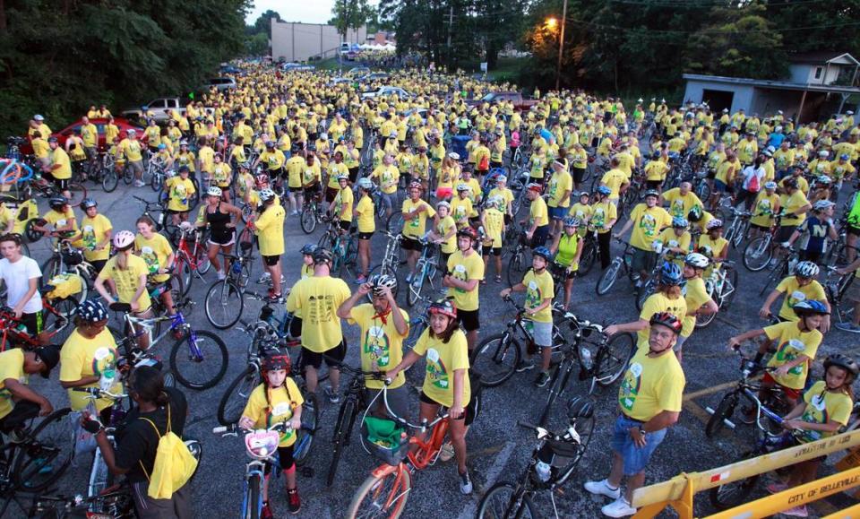 Bicyclists in matching yellow T-shirts listen to music at a party before the ride.