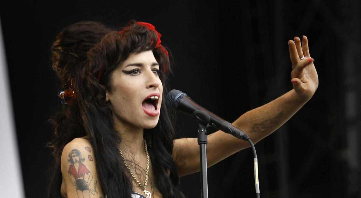 FILE - In this Aug. 17, 2008 file photo, British singer Amy Winehouse performs at the V Festival in Chelmsford, Essex. The first-ever Amy Winehouse exhibit in the U.S. will debut at the Grammy Museum in Los Angeles next month. The Recording Academy told The Associated Press on Thursday, Dec. 19, 2019, that the late British singer's popular outfits - including her halter dress worn at her final stage performance in Belgrade in 2011 - never-before-seen handwritten lyrics and home video, journal entries and more from her family's personal archive will make up “Beyond Black - The Style of Amy Winehouse.