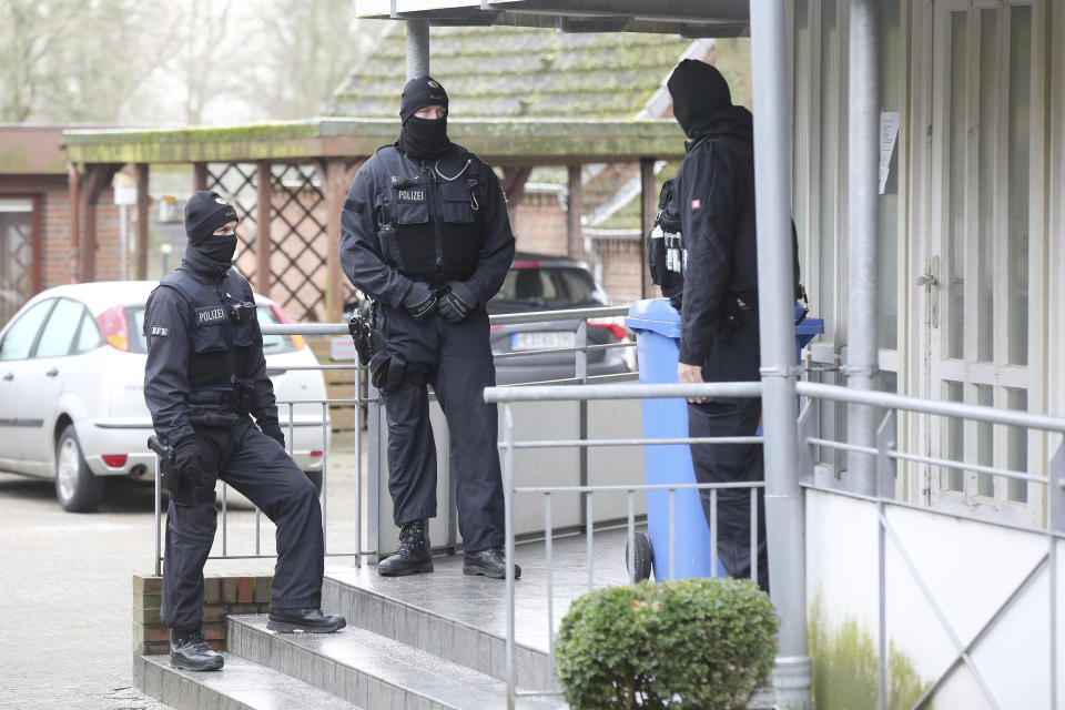 Police officer stand in front of at building during a raid in the village Meldorf, Germany, Jan. 30, 2019. German authorities arrested three suspected Islamic extremist Iraqi men in the norther German costal region, on allegations they were planning a bombing. (Bodo Marks/dpa via AP)