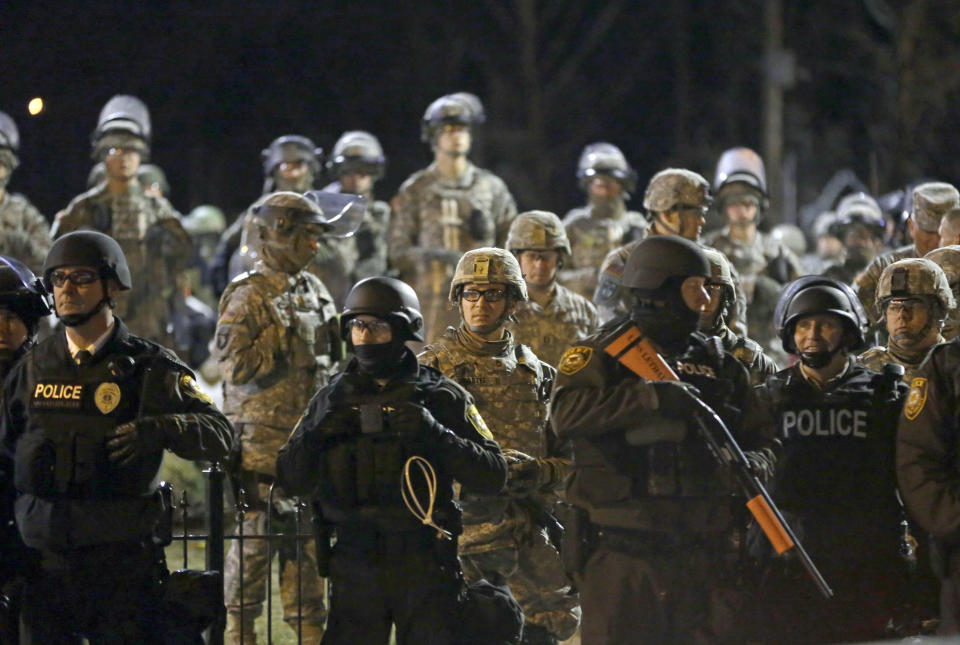 FILE - In this Friday, Nov. 28, 2014, file photo, police and Missouri National Guardsmen stand guard as protesters gather in front of the Ferguson Police Department, in Ferguson, Mo. In Ferguson, police drew heavy criticism for their militarized response to protests after unarmed 18-year-old Michael Brown, who was black, was fatally shot by white officer Darren Wilson, who was not charged and later resigned. Police have given demonstrators in the latest St. Louis protests a wide berth, applying a lesson learned in nearby Ferguson to offer protesters ample room to have their say, at least until trouble starts. (AP Photo/Jeff Roberson, File)