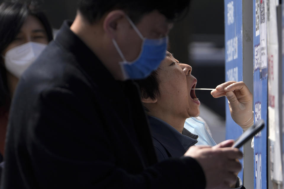 Residents line up to get their throat swab at a coronavirus testing site, Tuesday, April 5, 2022, in Beijing. China has sent more than 10,000 health workers from across the country to Shanghai, including 2,000 military medical staff, as it struggles to stamp out a rapidly spreading COVID-19 outbreak in China's largest city. (AP Photo/Andy Wong)