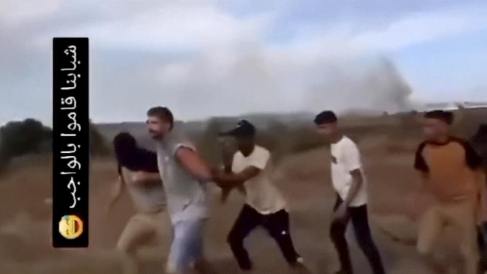 In this image from video obtained by the AP, Avinatan Or, second left, and his partner, Noa Argamani, not pictured, are seized by members of the Hamas militant group during an incursion into Israel on Saturday, Oct. 7, 2023. Israeli media reported that the couple had been attending a dance music festival in the desert when militants overran the area. The writing in Arabic at left in the video posted on social media reads, "Our guys have done their duty" (AP Photo)