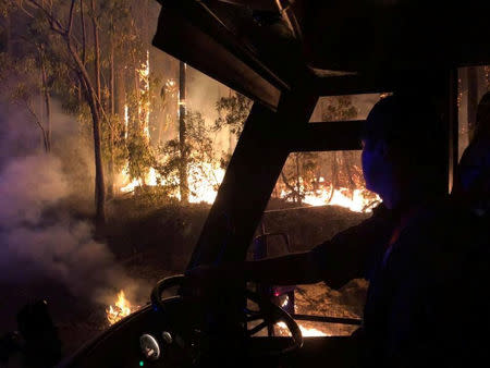 A firefighter sits in a fire engine as he watches a bushfire in New South Wales, Australia, August 16, 2018, in this picture obtained from social media. Fire and Rescue NSW/via REUTERS