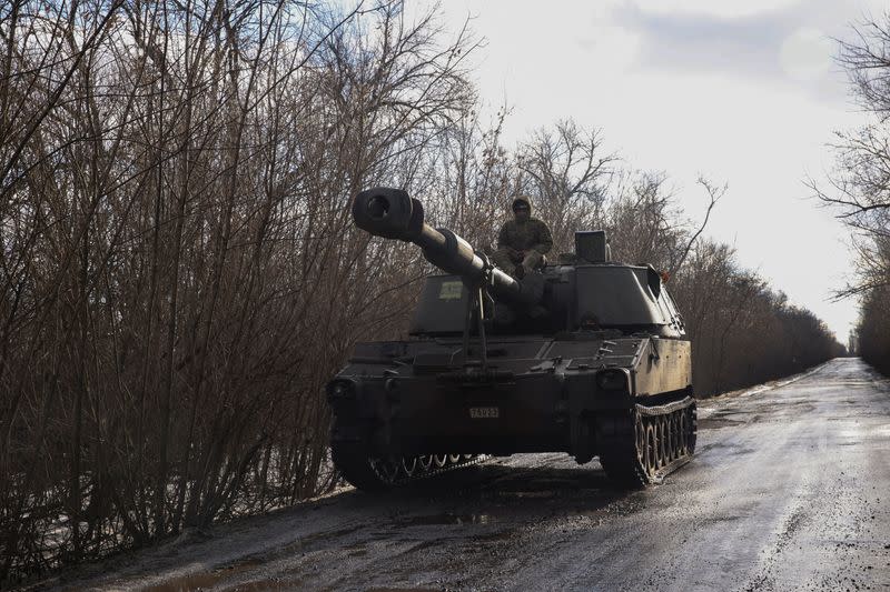 Ukrainian servicemen ride a self-propelled howitzer outside the town of Siversk