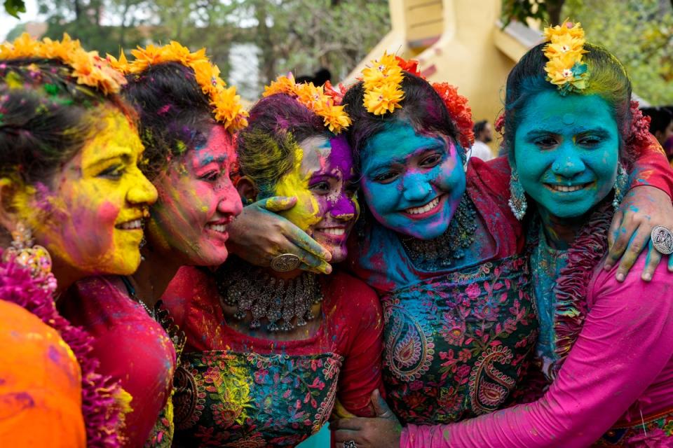 Women, with their faces smeared with coloured powder, pose for a photograph as they celebrate Holi, the festival of colors, in Kolkata, India (AP)
