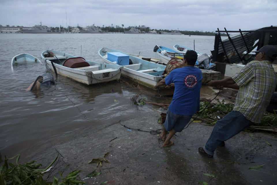 Fishermen try to pull in a boat that was flooded by Hurricane Rick in Lazaro Cardenas, Mexico, Monday, Oct. 25, 2021. Hurricane Rick roared ashore along Mexico's southern Pacific coast early Monday with winds and heavy rain amid warnings of potential flash floods in the coastal mountains. (AP Photo/Armando Solis)