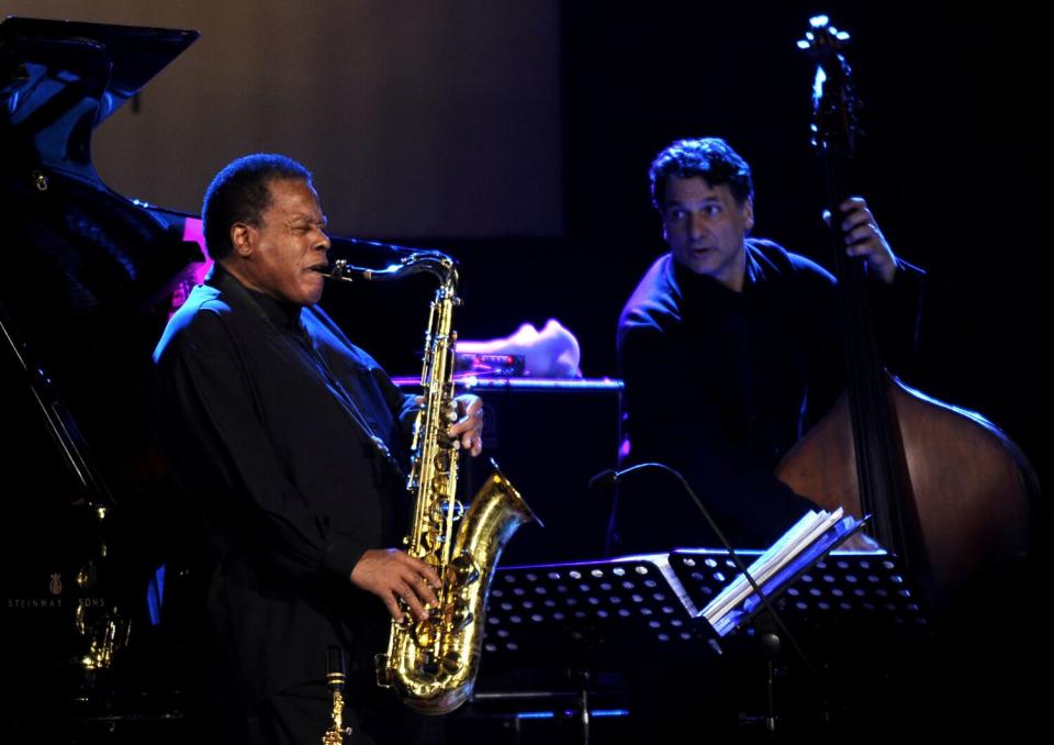 A man plays a saxophone next to a bass player onstage at a jazz festival.