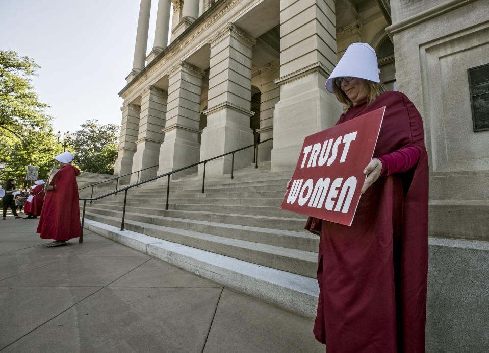 File-Michelle Disher, from Roswell, and others dressed as characters from "The Handmaid's Tale", protest outside the Capitol where Georgia's Republican Gov. Brian Kemp, was to sign the legislation, Tuesday, May 7, 2019, in Atlanta, banning abortions once a fetal heartbeat can be detected, which can be as early as six weeks before many women know they're pregnant. A federal judge is permanently blocking Georgia’s 2019 “heartbeat" abortion law, finding that it violates the U.S. Constitution. U.S. District Judge Steve Jones ruled against the state Monday, July 13, 2020, in a lawsuit filed by abortion providers and an advocacy group. (Bob Andres/Atlanta Journal-Constitution via AP, File)