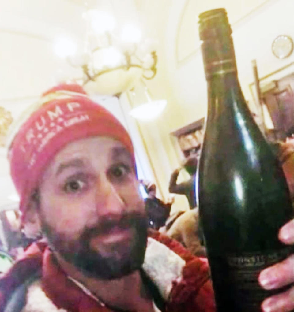 Jason Riddle holds a bottle of wine inside the Capitol. (via NBC Boston)