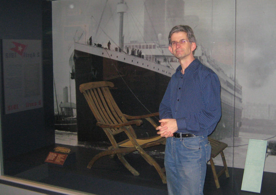 In this Feb. 28, 2012 photo, Gerry Lunn, curator of the Maritime Museum of the Atlantic in Halifax, Nova Scotia, Canada, stands next to a Titanic deck chair given to the minister who performed services on one of the ships that recovered bodies. Lunn said the city was in mourning for months after the disaster. One hundred years ago, ships from this old port city on the Atlantic set out to recover the Titanic's dead. They brought back more than 330 bodies; 150 are buried in three Halifax cemeteries. (AP Photo/Robert Gillies)