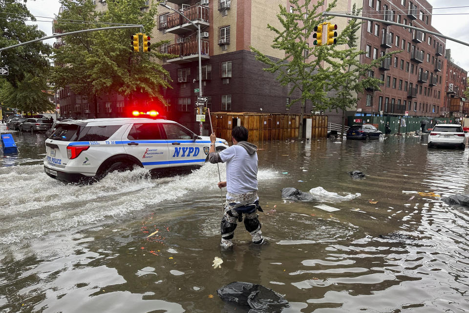 Un hombre intenta destapar una coladera en una zona inundada tras un aguacero en el distrito de Brooklyn, en Nueva York, el viernes 29 de septiembre de 2023. (AP Foto/Jake Offenhartz)