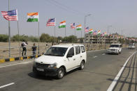 Police vehicles moves past U.S. and Indian flags erected near Sardar Patel stadium ahead of the visit of President Donald Trump in Ahmedabad, India, Sunday, Feb. 23, 2020. The sun-baked northwestern Indian city was jostling with activity Sunday as workers cleaned roads, planted flowers and hoisted hundreds of billboards featuring President Donald Trump, a day ahead of his maiden two-day visit to India after Prime Minister Narendra Modi promised him a boisterous public reception. (AP Photo/Ajit Solanki)