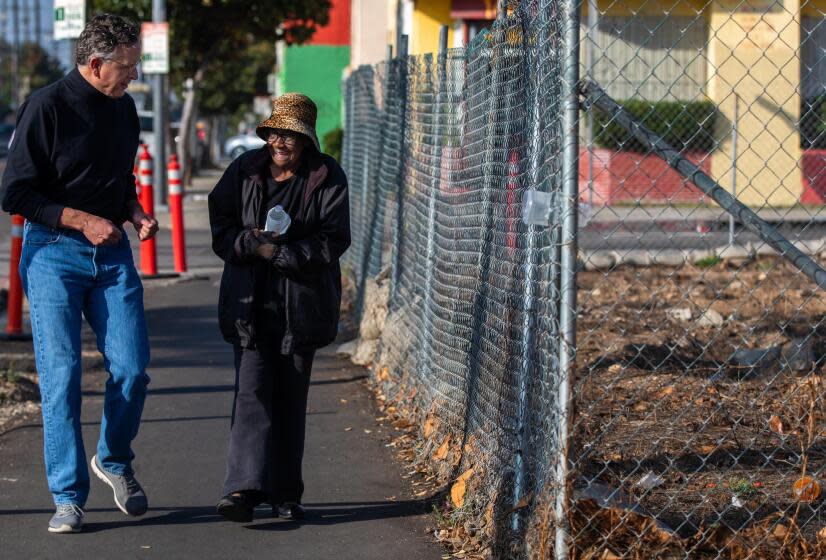 Los Angeles, CA - Richard Parks, left, President of the South L.A. nonprofit Redeemer Community Partnership, walks with neighbor QC Kelker, right, next to a field on Jefferson Blvd. Thursday, Dec. 7, 2023, in Los Angeles, CA. After a years-long neighborhood battle against an oil drilling site in South Los Angeles, a local nonprofit has purchased the now-demolished facility and plans to transform it into a park, community center, and affordable housing. (Francine Orr / Los Angeles Times)