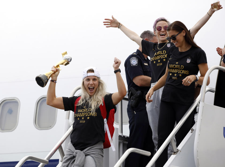 Members of the United States women's soccer team, winners of a fourth Women's World Cup, including Julie Ertz, left, Megan Rapinoe, top center, and Alex Morgan, top right, celebrate after arriving at Newark Liberty International Airport, Monday, July 8, 2019, in Newark, N.J. (AP Photo/Kathy Willens)