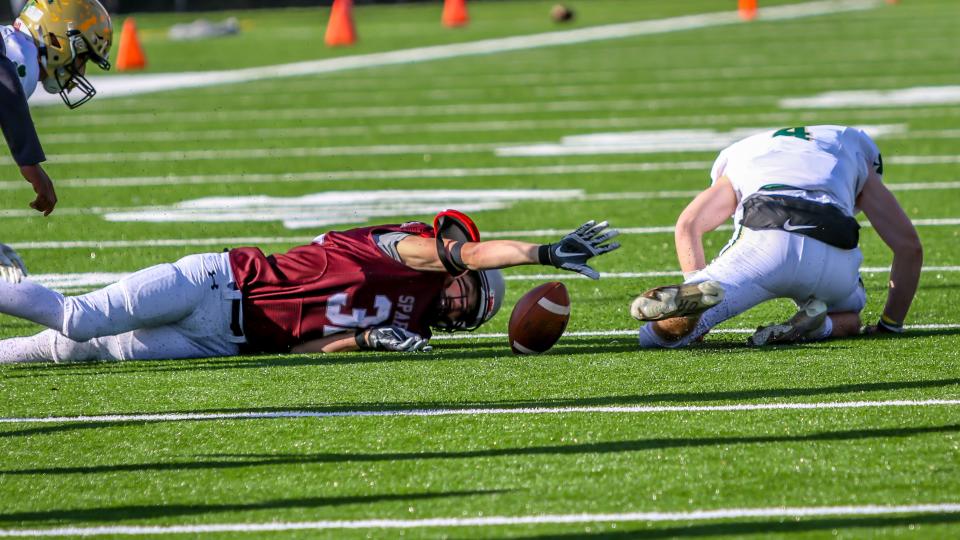 Bishop Stang's Luke Grigsontries to gather in a fumble by Feehan quarterback Aidan Crump. Bishop Stang recovered the fumble.