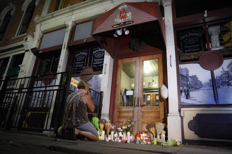 FILE—Mourners visit a makeshift memorial Sunday, Aug. 4, 2019, outside Ned Peppers bar following a vigil at the scene of the mass shooting in Dayton, Ohio. As the anniversary of the 2019 shooting approaches, the mayor talks about plans to mark the day, Dion Green whose father died in the mass shooting on a night with him, wrote a book about surviving tornadoes that shooting and new murals adorn the walls of buildings in the city's Oregon Entertainment District. (AP Photo/John Minchillo, File)