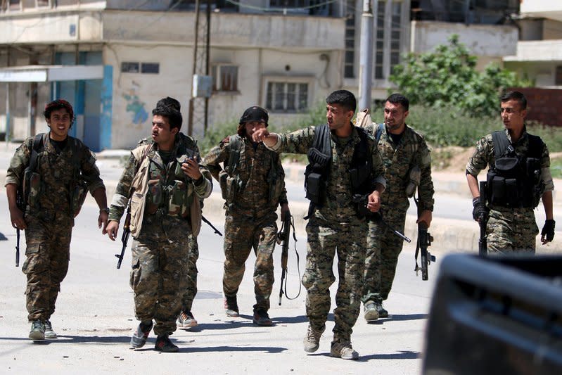 Kurdish fighters from the People's Protection Units (YPG) walk along a street in the southeast of Qamishli city, Syria, April 22, 2016. REUTERS/Rodi Said