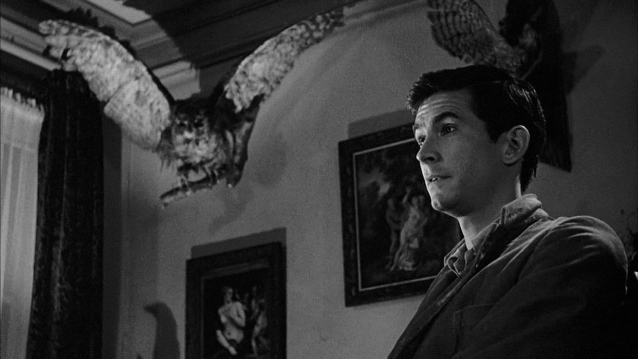 norman bates stands with a slight smile on his face in a scene from psycho, a good housekeeping pick for best halloween movies