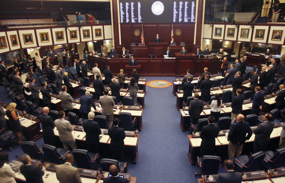 FILE - Members of the House of Representatives rise for prayer at the opening of a special session, Aug. 7, 2014, at the Capitol in Tallahassee, Fla. A stripper and the strip club where she worked have sued Florida’s attorney general to stop enforcement of a new state law took effect on Monday, July 1, 2024, that prohibits adult entertainment businesses from employing people who are under age 21, claiming it violates their First Amendment rights. (AP Photo/Phil Sears, File)