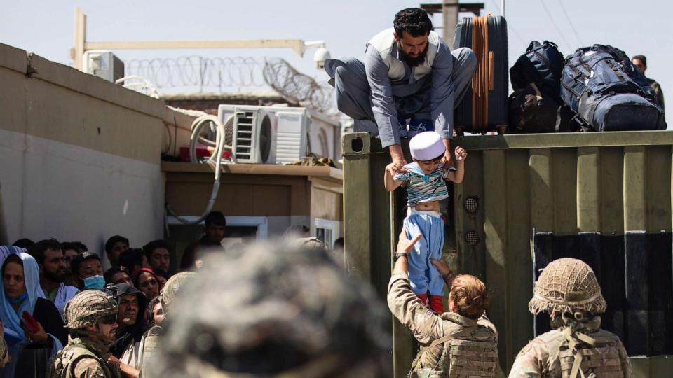 PHOTO: An Afghan man hands his child to a British Paratrooper assigned to 2nd Battalion, Parachute Regiment while a member of 1st Brigade Combat Team, 82nd Airborne Division conducts security at Hamid Karzai International Airport in Kabul, Aug. 26, 2021. (U.S. Army via AP, FILE)