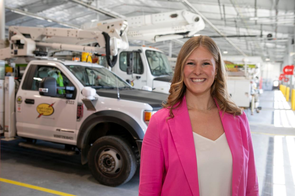 Emily Cordle, community relations specialist, stands in front of the bucket trucks inside of a garage at the South Central Power Company on April 22, 2024, in Lancaster, Ohio. Cordle won the Young Professionals Award this year.