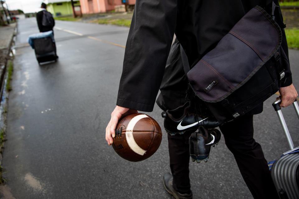 Elder Tanner McKee, a missionary for The Church of Jesus Christ of Latter-day Saints, walks to the bus, toting a football, cleats and a suitcase, as he transfers from Paranaguá, Brazil, to another area of the Curitiba South mission on Monday, June 3, 2019. | Spenser Heaps, Deseret News