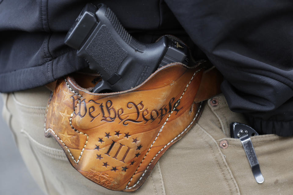 FILE - An attendee at a gun rights rally open carries his gun in a holster that reads "We the People" from the Preamble to the United States Constitution, Friday, Jan. 18, 2019, at the Capitol in Olympia, Wash. After a gunman killed 19 children and two teachers at an elementary school in Uvalde, Texas, on May 24, 2022, several pastors and rabbis around the country have challenged their conservative counterparts with this question: Are you pro-life if you are pro-guns? (AP Photo/Ted S. Warren, File)