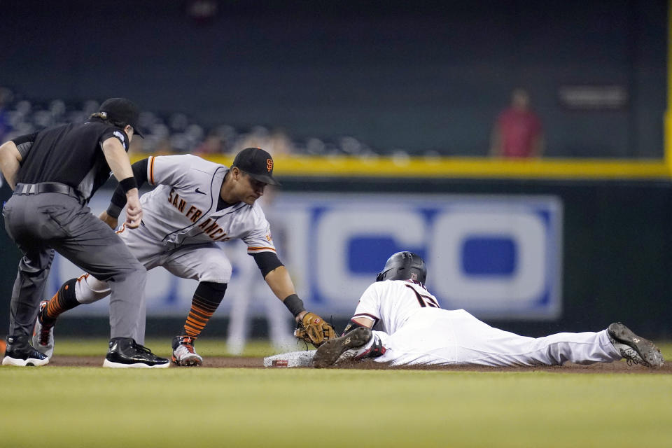 Arizona Diamondbacks' Nick Ahmed, right, slides safely into second base with a double as San Francisco Giants second baseman Donovan Solano, middle, applies a late tag while umpire Chris Guccione, left, looks on during the first inning of a baseball game, Thursday, Aug. 5, 2021, in Phoenix. (AP Photo/Ross D. Franklin)