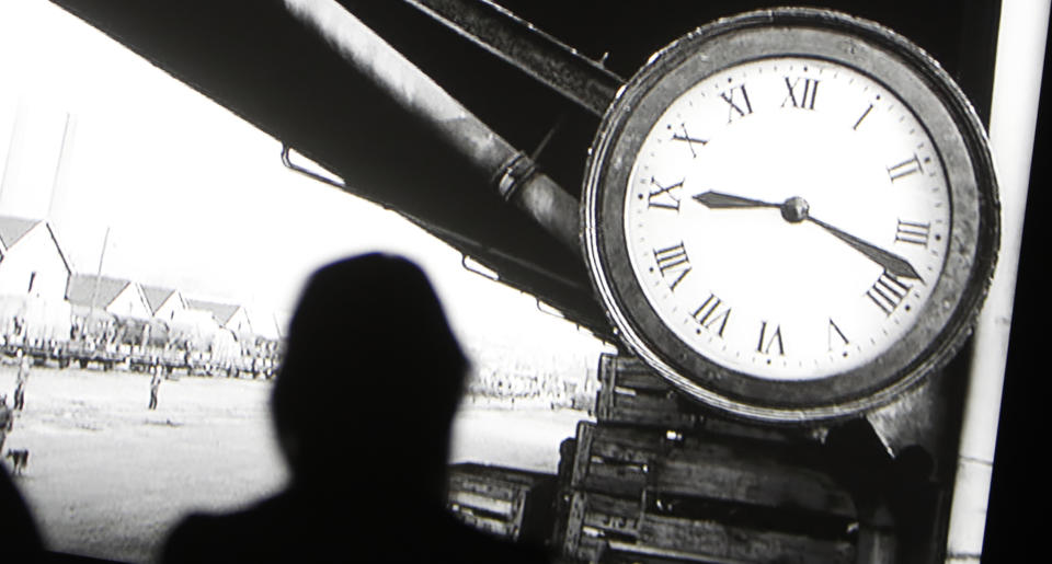 People watch a section of the 24 hour video installation by Christian Marclay, which is entitled ' The Clock' at the Tate Modern in London, Tuesday, Sept. 11, 2018. Christian Marclay's "The Clock" is both the ultimate movie, and an artwork you can set your watch by. The Swiss-American artist has edited together thousands of film clips containing clocks, watches or references to the time _ one or more for every minute of the day _ into a 24-hour video. It’s a mesmerizing patchwork that moves forward in time as it dances back and forth across film history. (AP Photo/Alastair Grant)